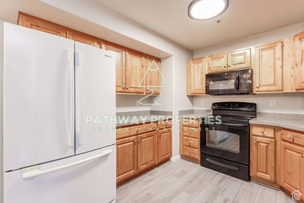 Kitchen featuring black appliances, light countertops, light wood-style floors, and light brown cabinetry
