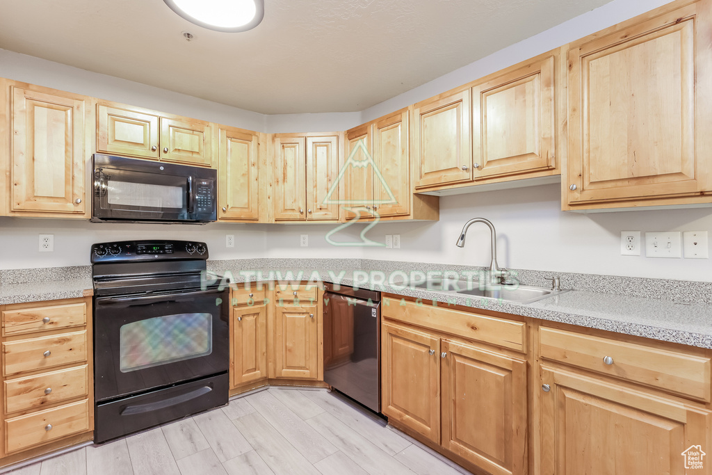 Kitchen with black appliances, a sink, and light brown cabinets