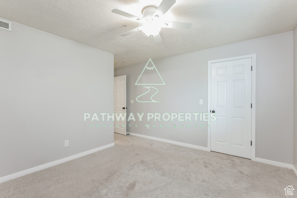 Unfurnished room with ceiling fan, light colored carpet, a textured ceiling, and baseboards