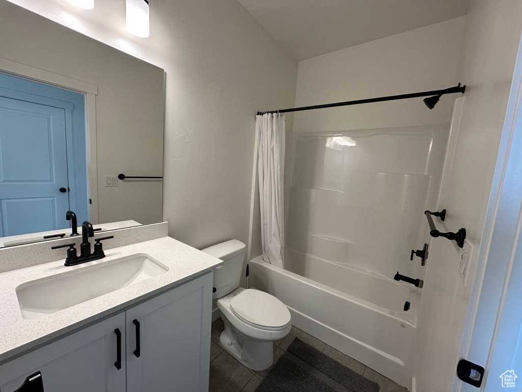 Bathroom featuring tile patterned flooring, toilet, vanity, and shower / bathtub combination with curtain