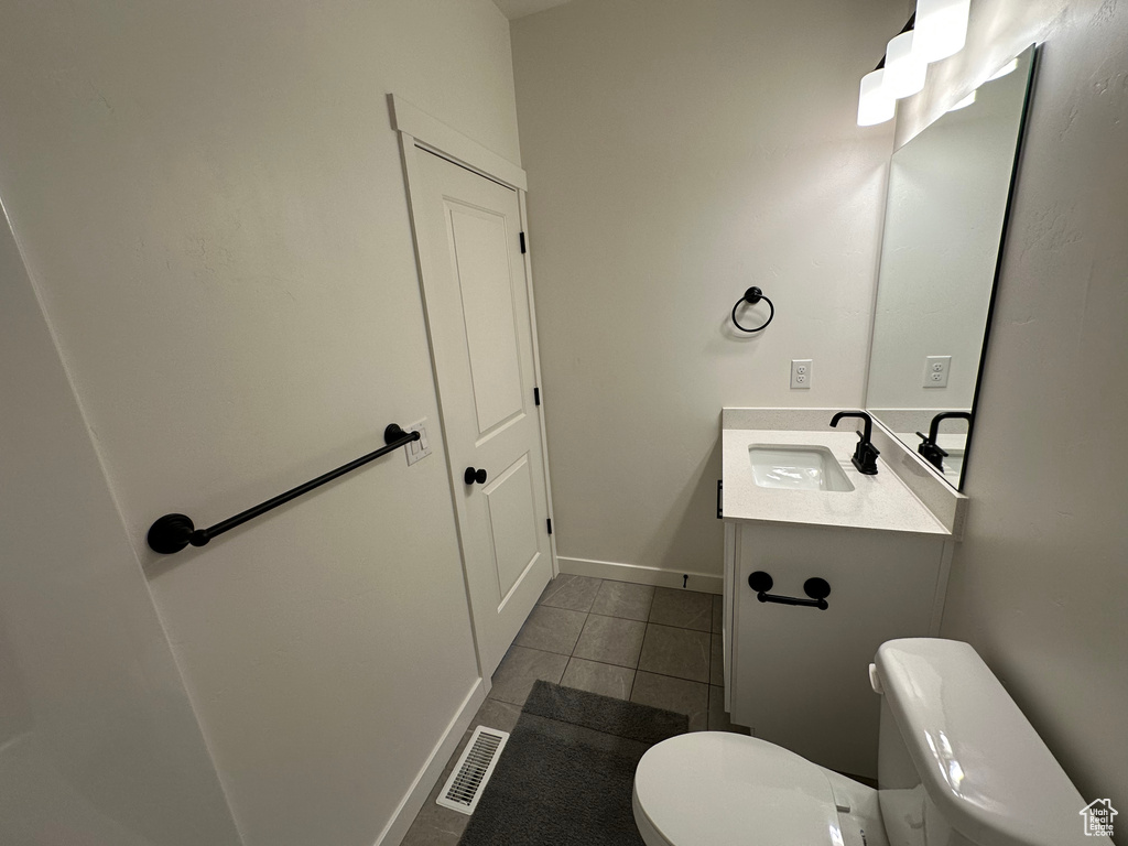 Half bathroom featuring toilet, tile patterned flooring, vanity, and baseboards