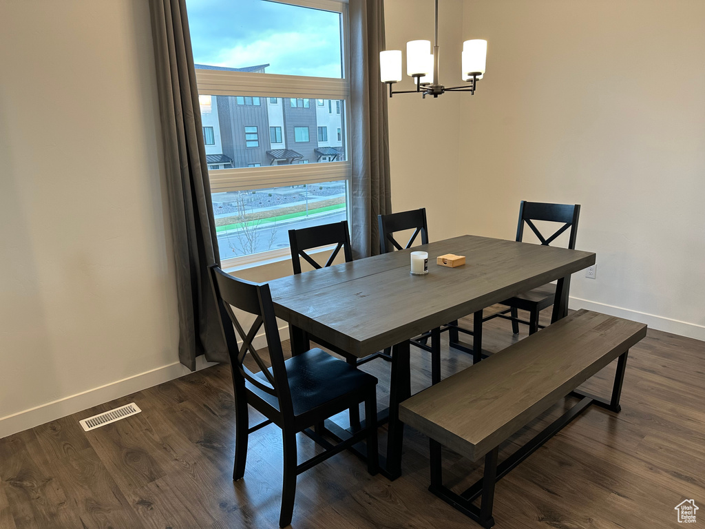 Dining space with baseboards, a chandelier, and dark wood-type flooring