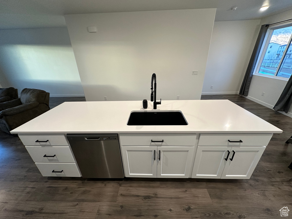 Kitchen featuring dishwasher, a sink, dark wood finished floors, baseboards, and white cabinets