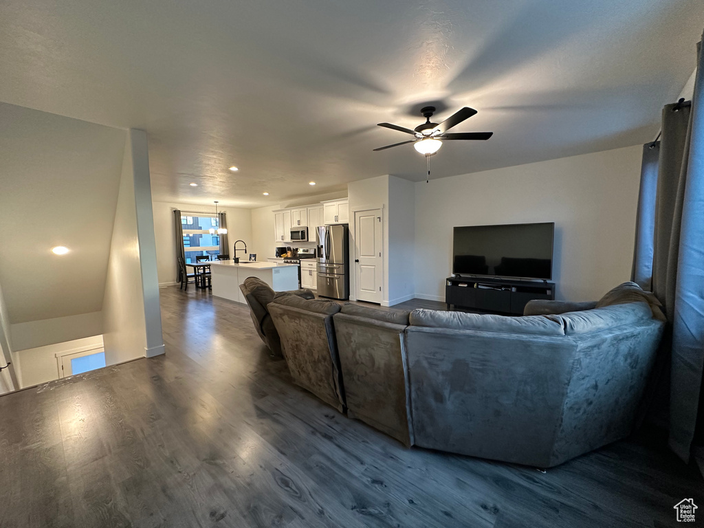 Living area with a ceiling fan, dark wood finished floors, baseboards, and recessed lighting