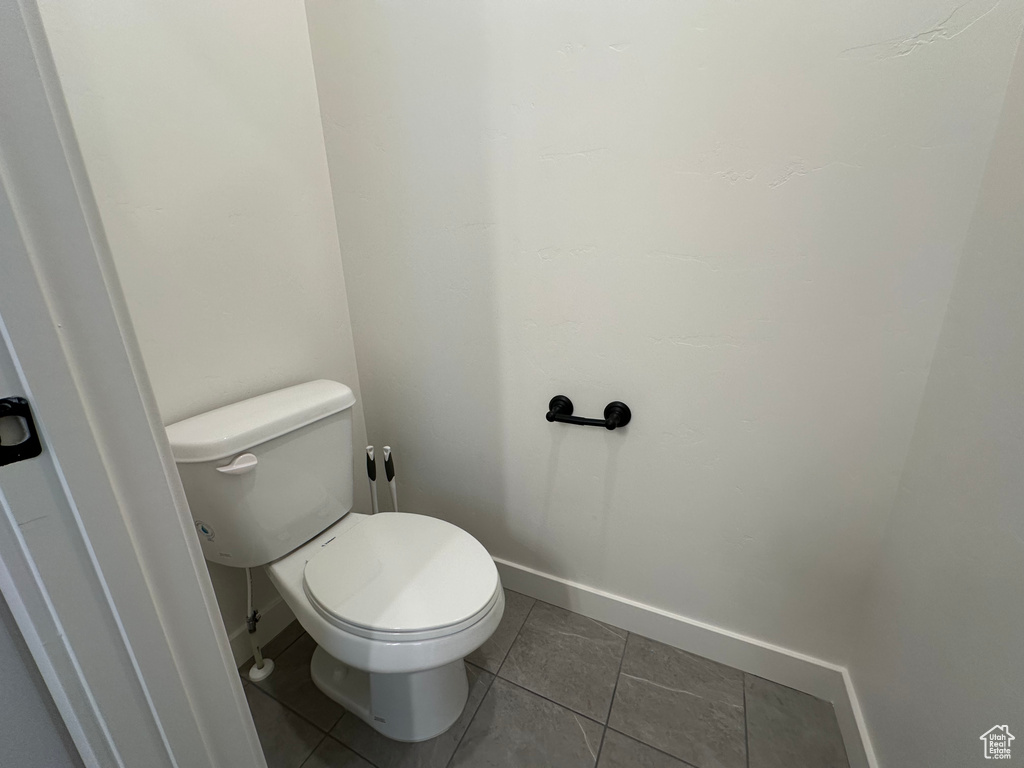 Bathroom featuring baseboards, tile patterned floors, and toilet