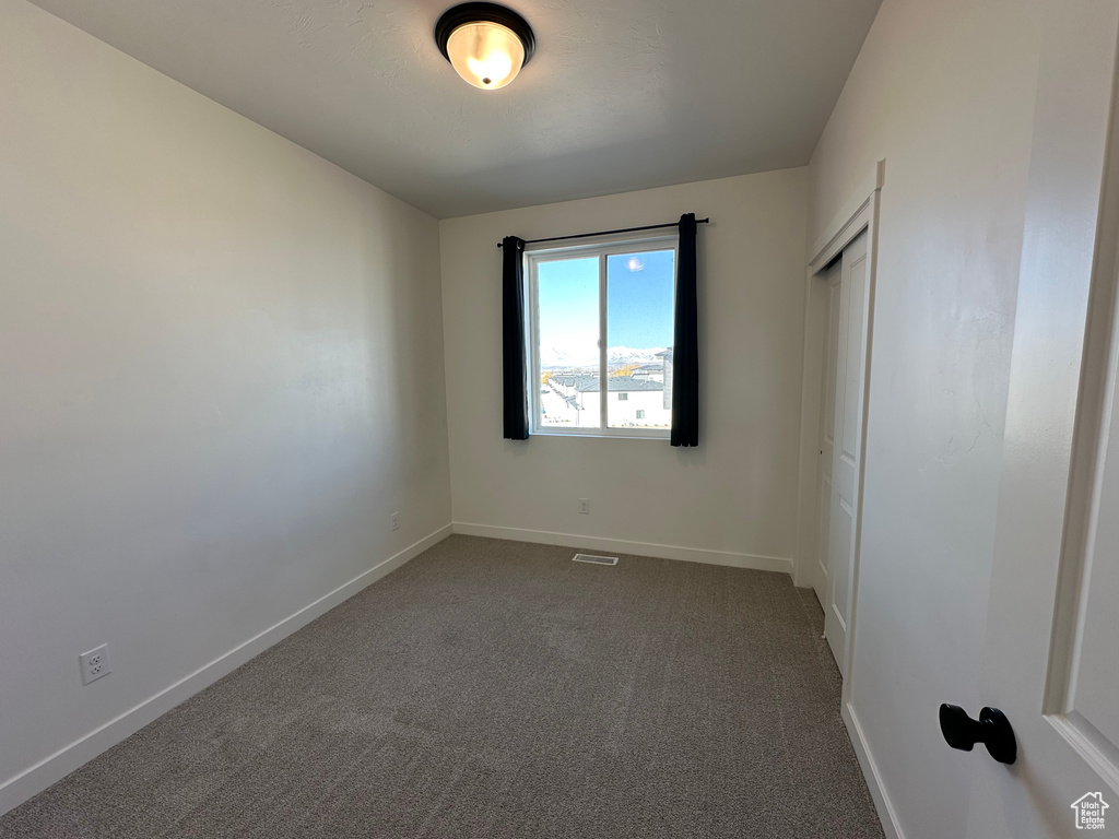 Empty room featuring dark colored carpet and baseboards