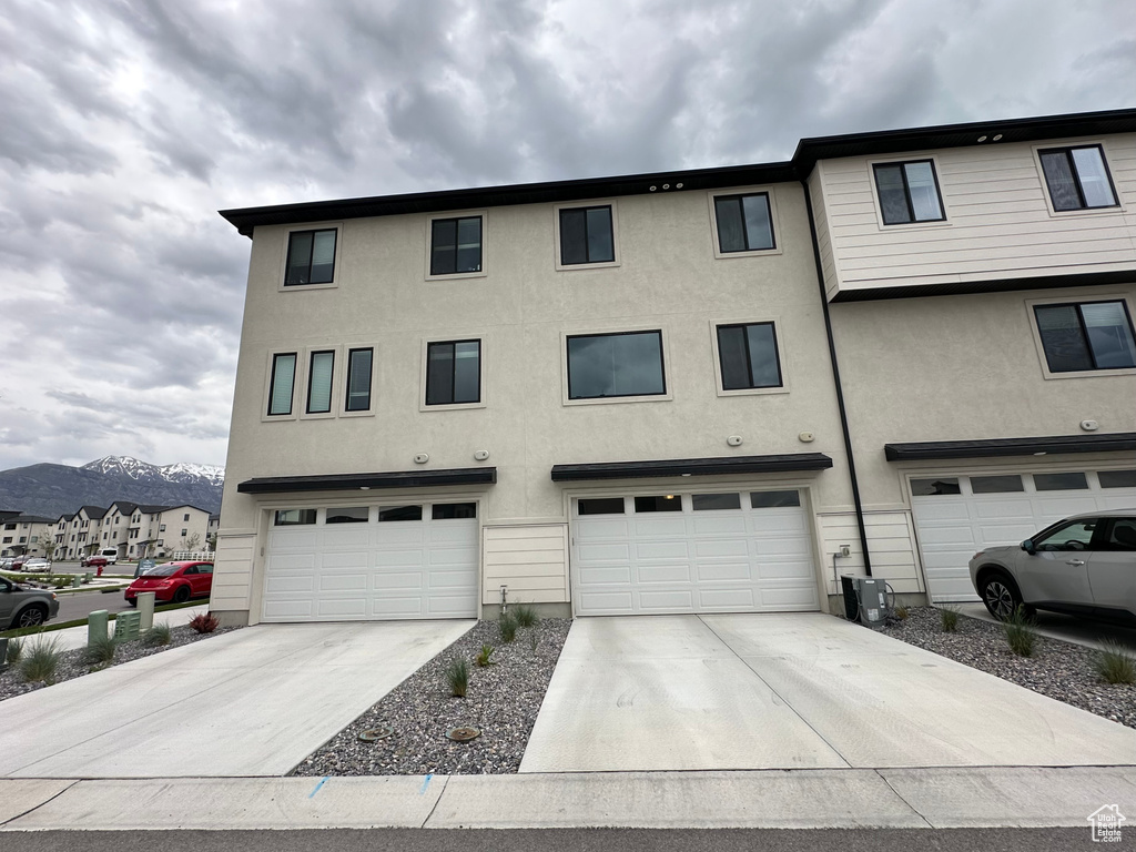 View of front of house featuring a garage, concrete driveway, stucco siding, and a mountain view