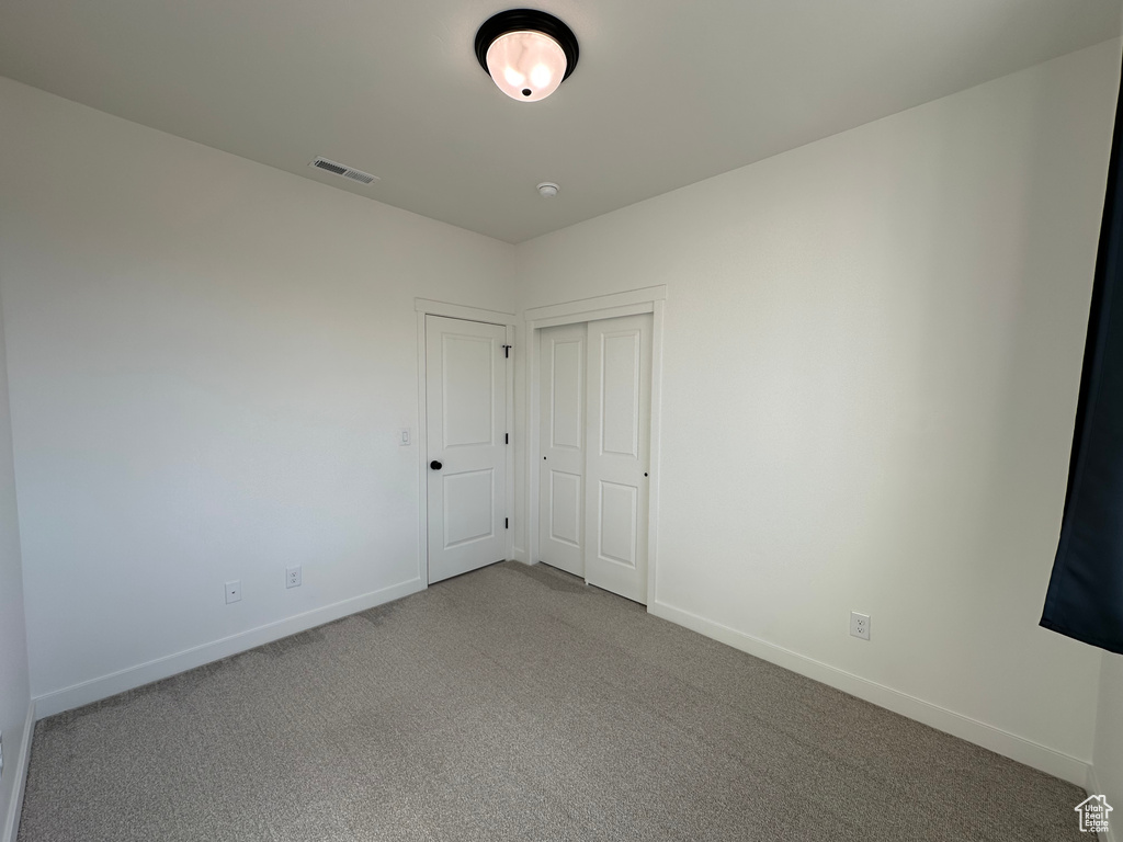 Unfurnished bedroom featuring baseboards, carpet, and a closet