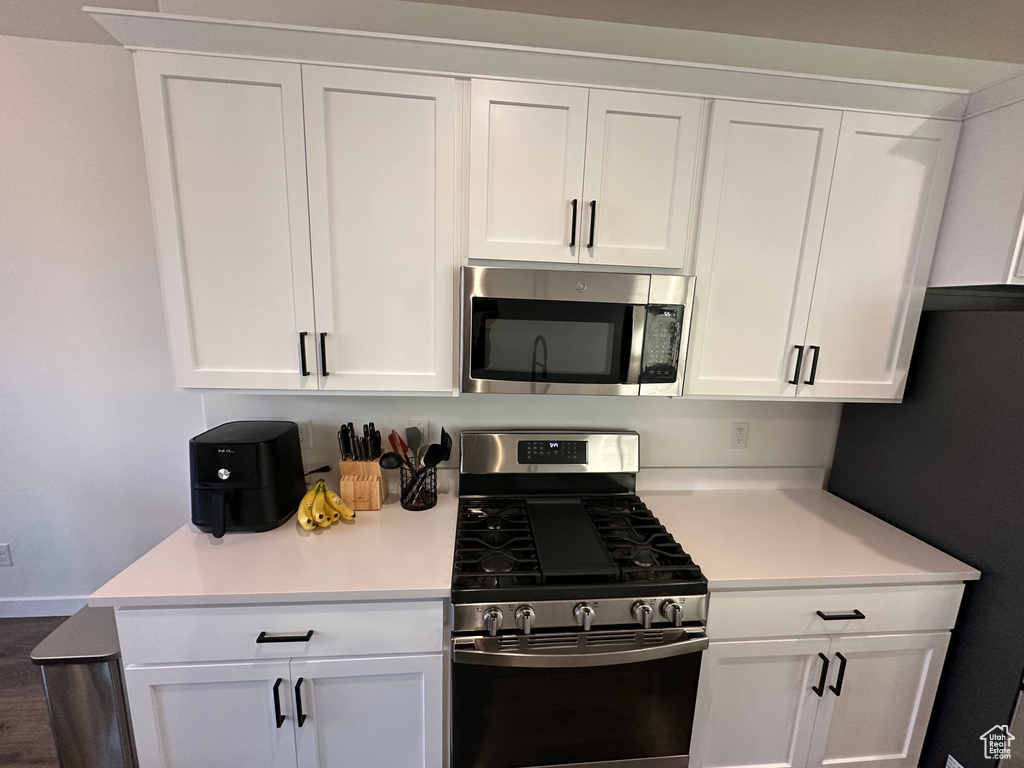 Kitchen with appliances with stainless steel finishes, white cabinets, and light countertops