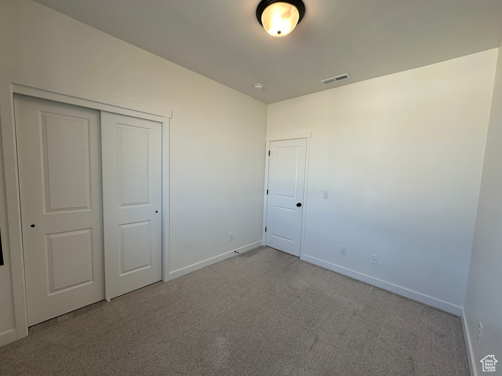 Unfurnished bedroom featuring carpet, baseboards, and a closet