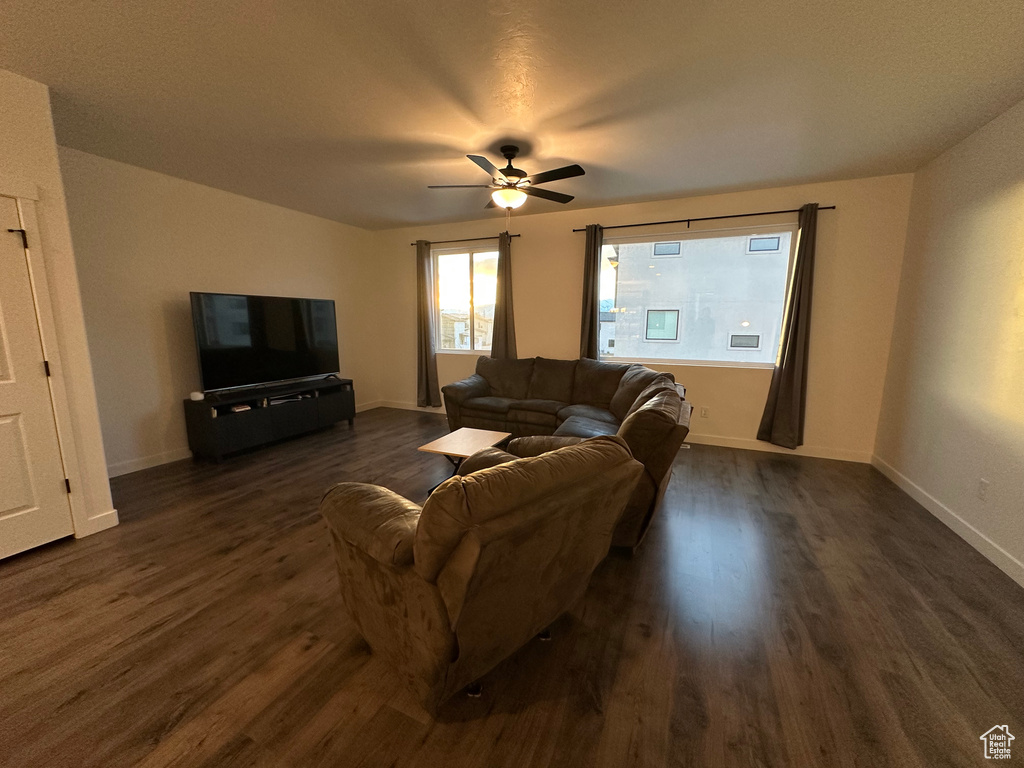 Living area featuring dark wood-style floors, ceiling fan, and baseboards