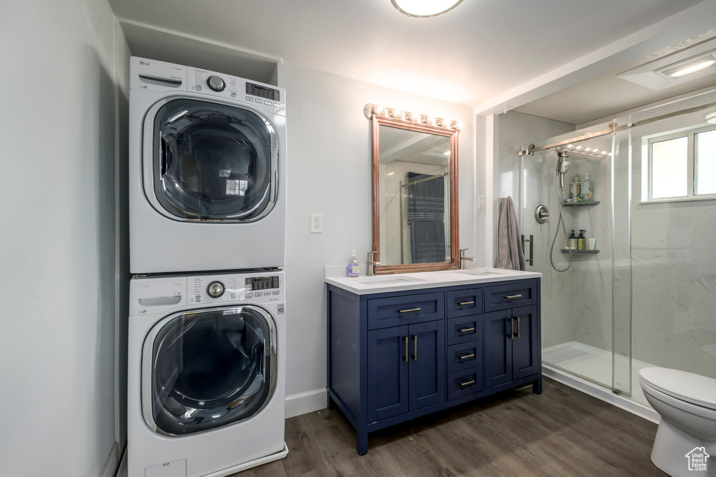 Laundry area featuring stacked washer / drying machine and dark wood-style floors