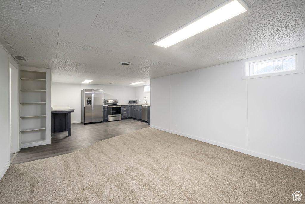 Unfurnished living room with dark carpet, baseboards, a textured ceiling, and dark wood-style flooring