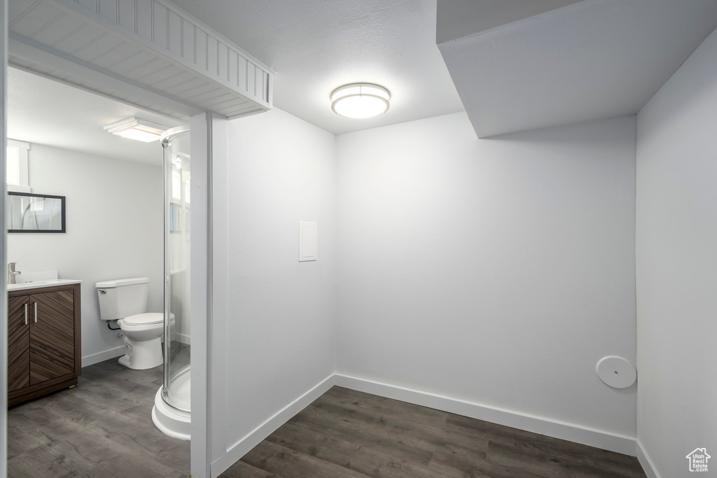 Full bathroom with wood finished floors, toilet, vanity, and baseboards