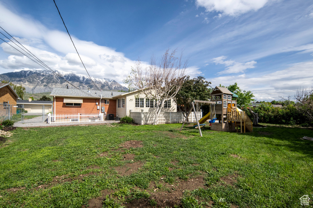 Rear view of property featuring a playground, a mountain view, and brick siding