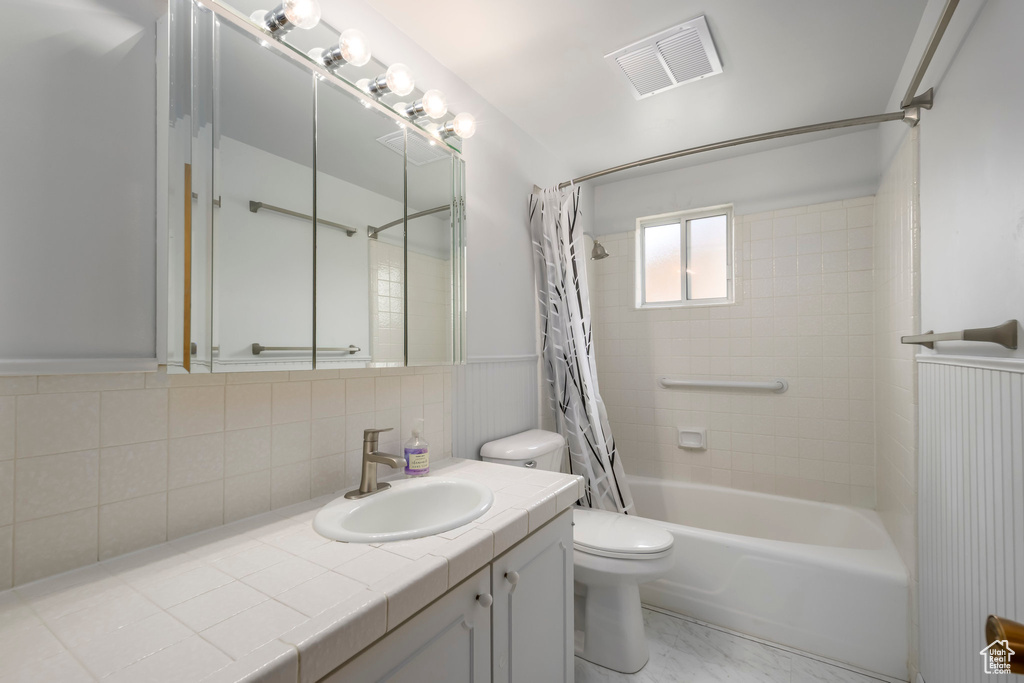 Bathroom featuring toilet, shower / tub combo with curtain, tasteful backsplash, and vanity