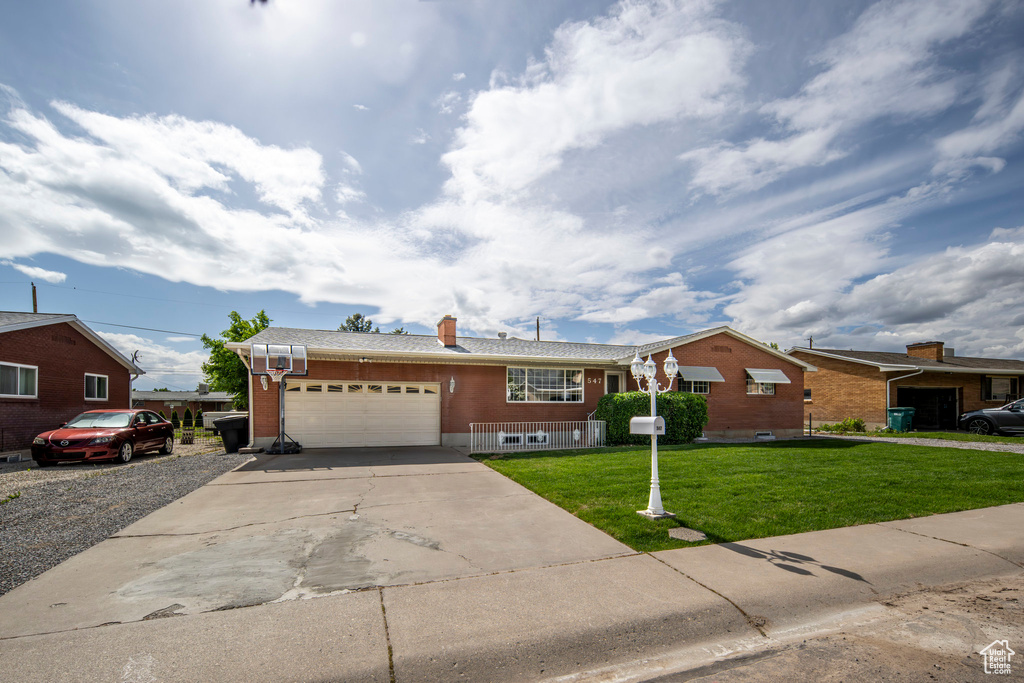 Ranch-style home with a garage, a front yard, concrete driveway, brick siding, and a chimney