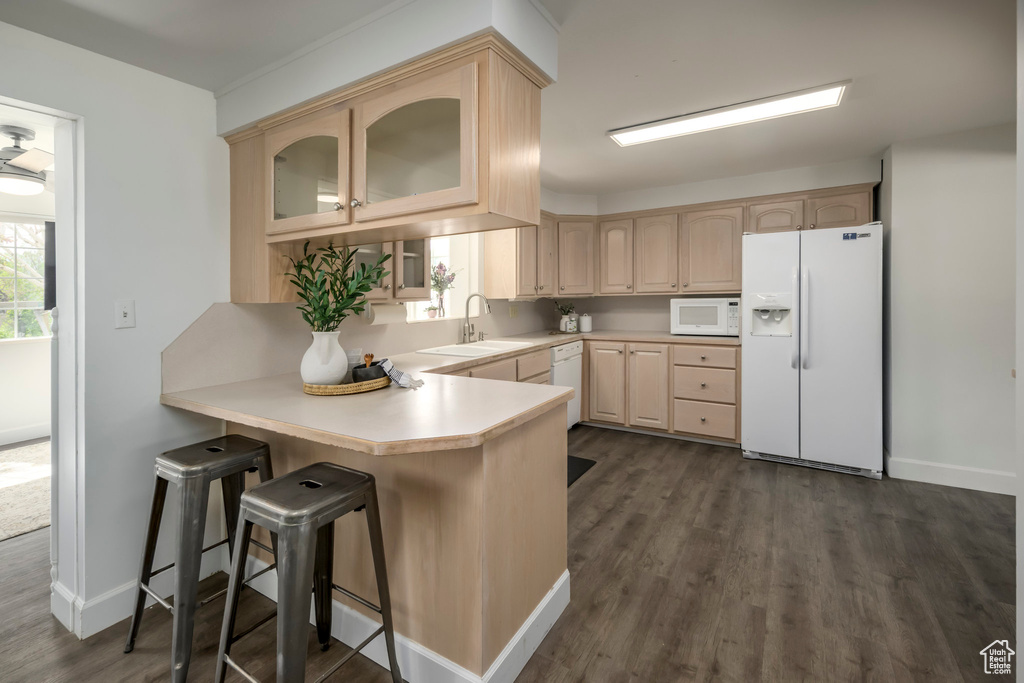 Kitchen with white appliances, light brown cabinetry, a peninsula, glass insert cabinets, and light countertops