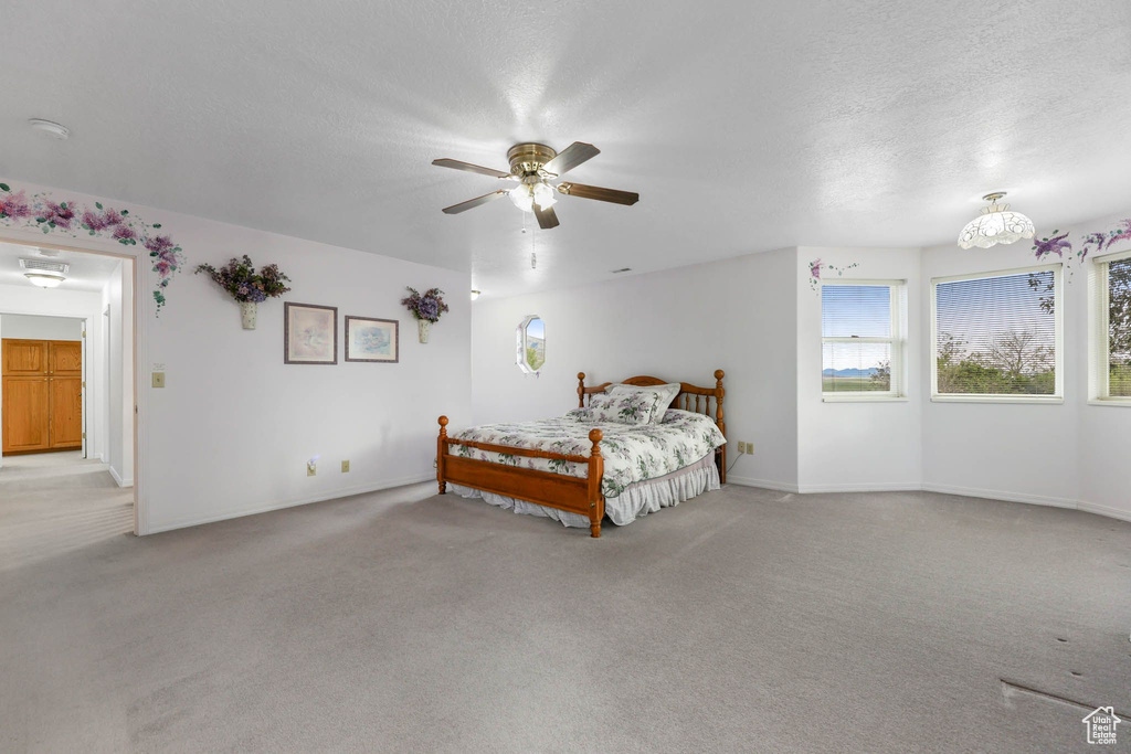 Bedroom with light carpet, a textured ceiling, baseboards, and a ceiling fan