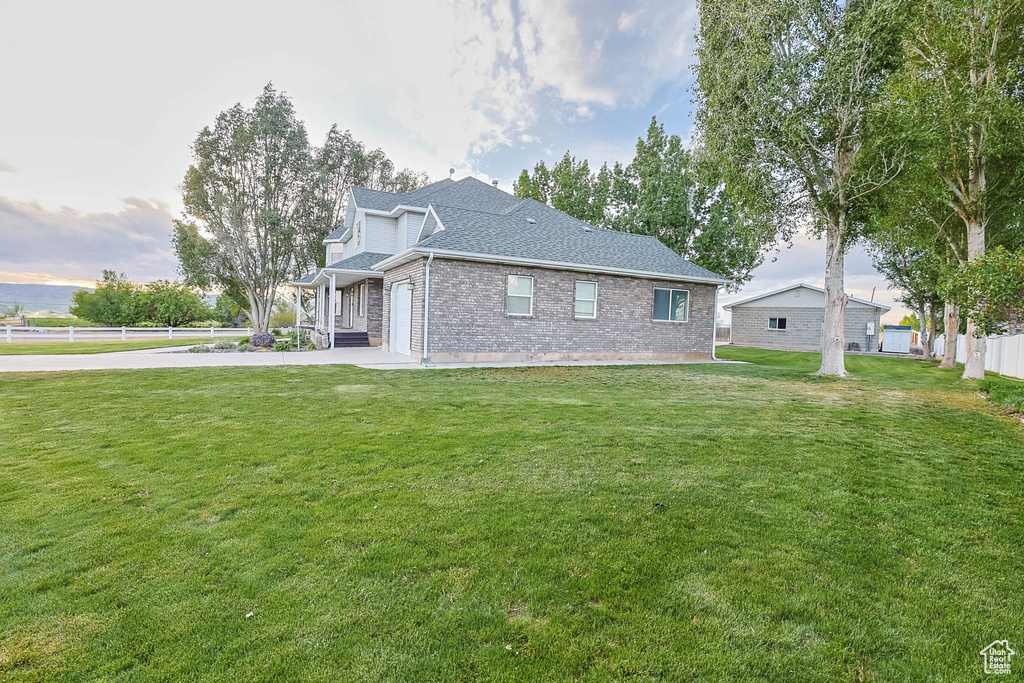 View of home\'s exterior with brick siding, driveway, roof with shingles, and a garage