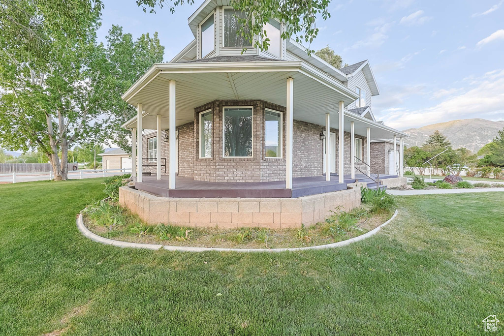 View of front of home with a porch, brick siding, a front lawn, and a mountain view