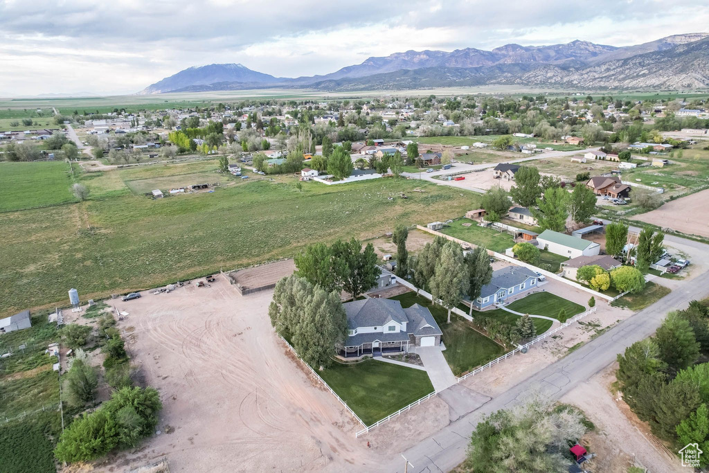 Aerial view of property and surrounding area featuring a mountainous background and nearby suburban area