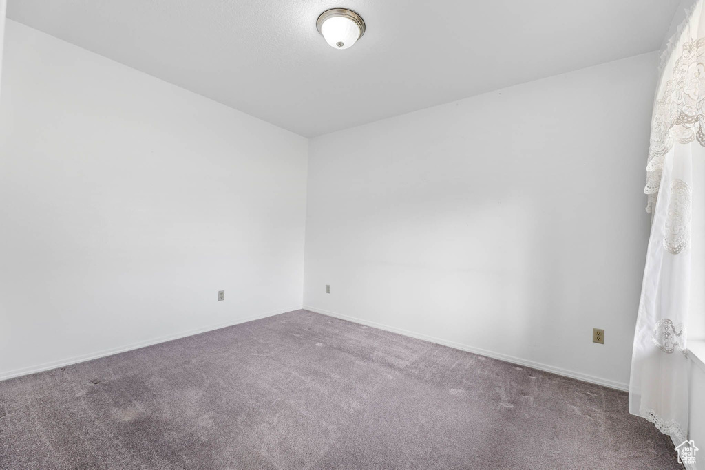 Carpeted empty room featuring baseboards