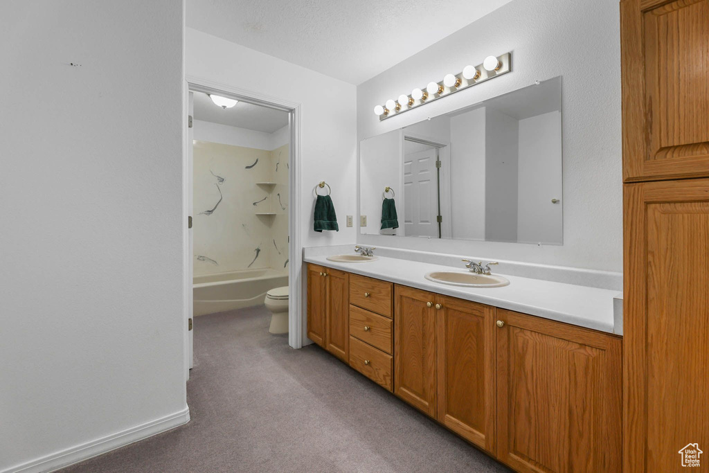 Full bathroom featuring double vanity, toilet, carpet flooring, and bathing tub / shower combination