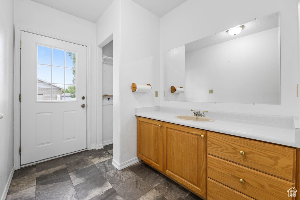 Bathroom featuring vanity, baseboards, and stone finish floors
