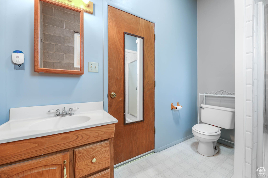 Bathroom with toilet, tile patterned floors, vanity, and baseboards