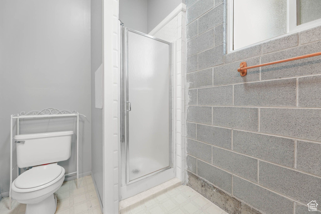 Bathroom featuring tile patterned floors, a shower stall, and toilet
