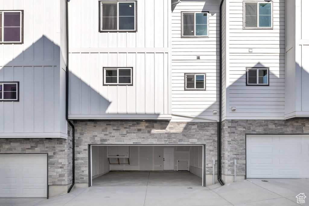 View of side of property with a garage, stone siding, board and batten siding, and driveway