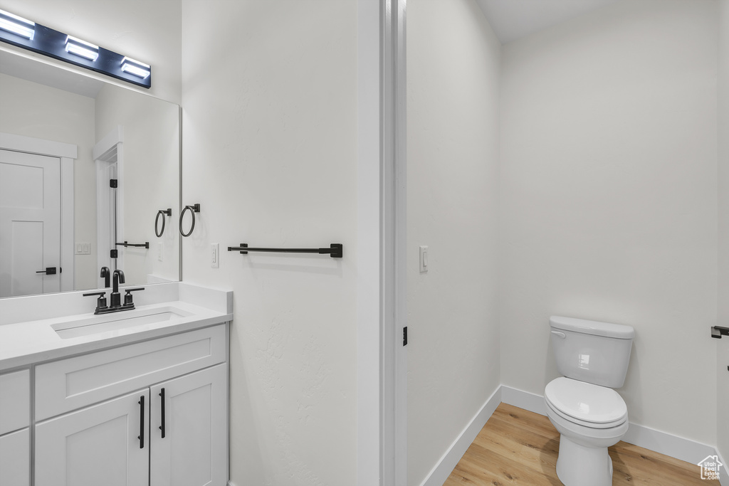 Bathroom with baseboards, wood finished floors, toilet, and vanity
