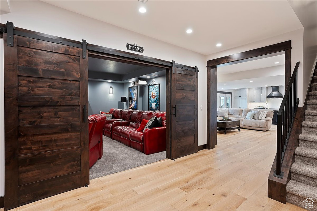 Living area featuring a barn door, stairway, light wood-type flooring, and recessed lighting