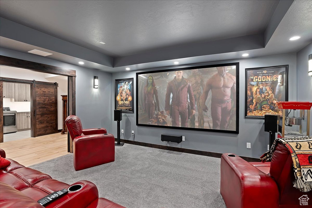 Cinema with recessed lighting, a barn door, baseboards, a raised ceiling, and wood finished floors