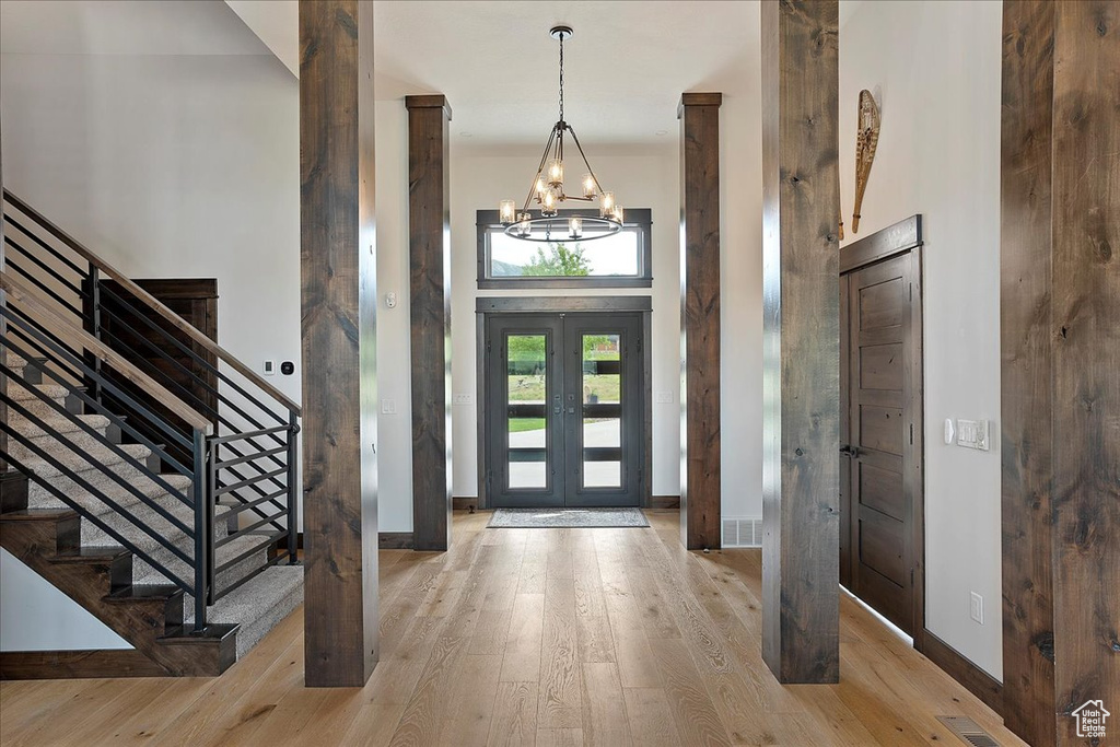 Foyer entrance featuring a chandelier, stairway, wood finished floors, a high ceiling, and baseboards