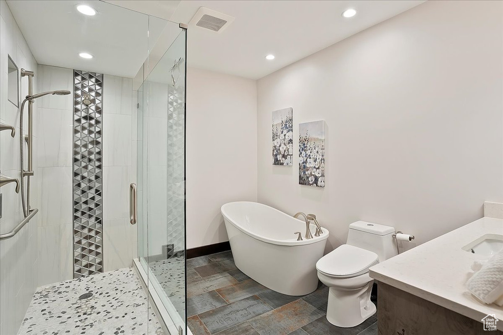 Full bath featuring a stall shower, a freestanding bath, recessed lighting, toilet, and vanity