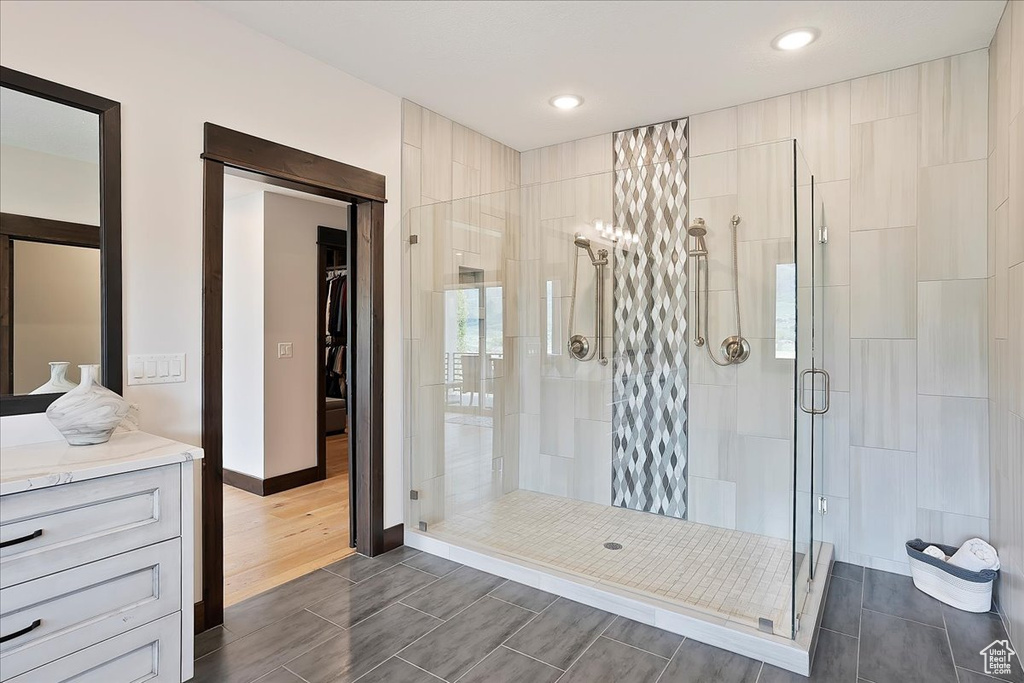 Bathroom featuring a shower stall, wood tiled floors, baseboards, recessed lighting, and vanity