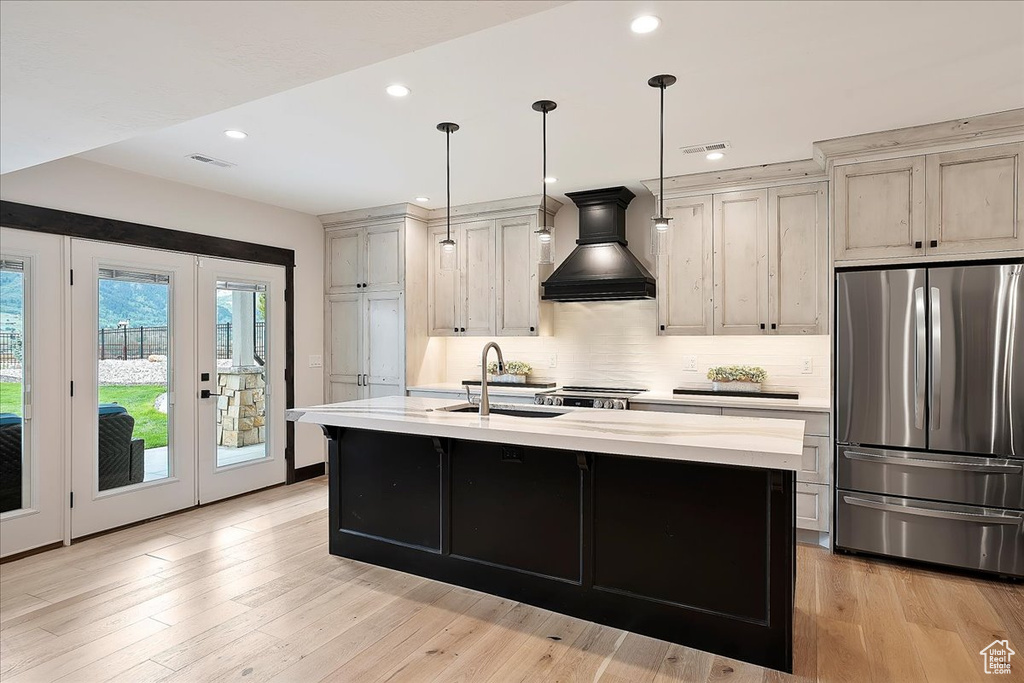 Kitchen featuring freestanding refrigerator, premium range hood, a sink, french doors, and light countertops