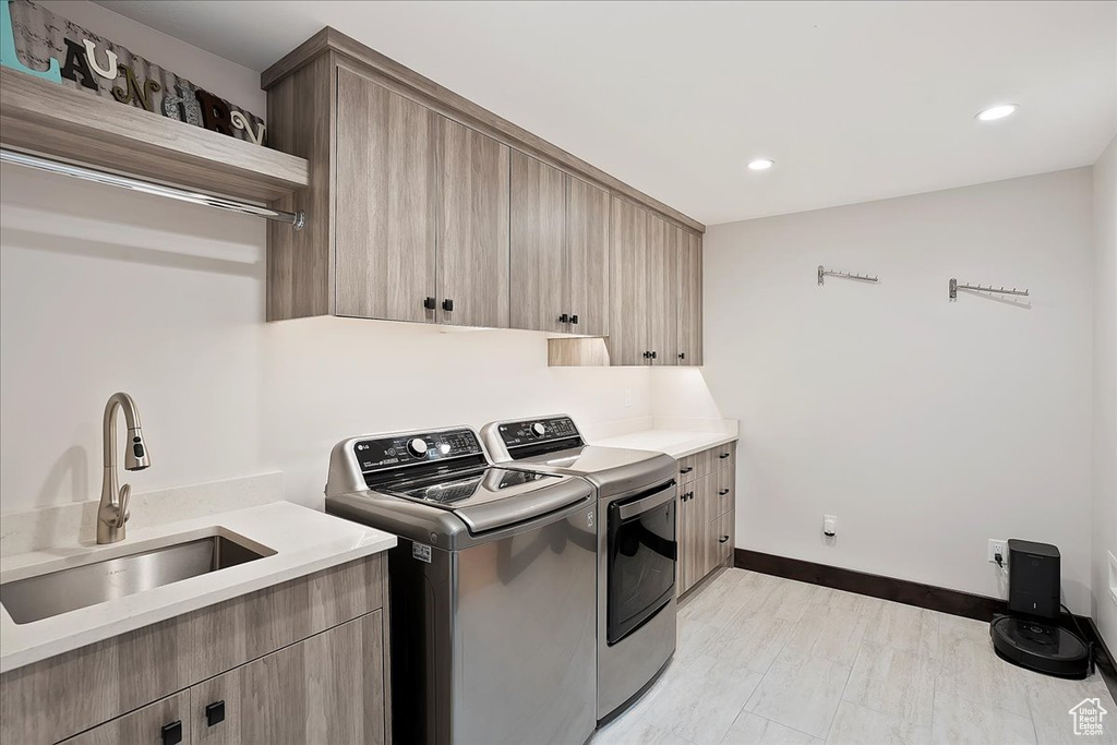 Clothes washing area featuring washer and clothes dryer, cabinet space, recessed lighting, baseboards, and light wood finished floors
