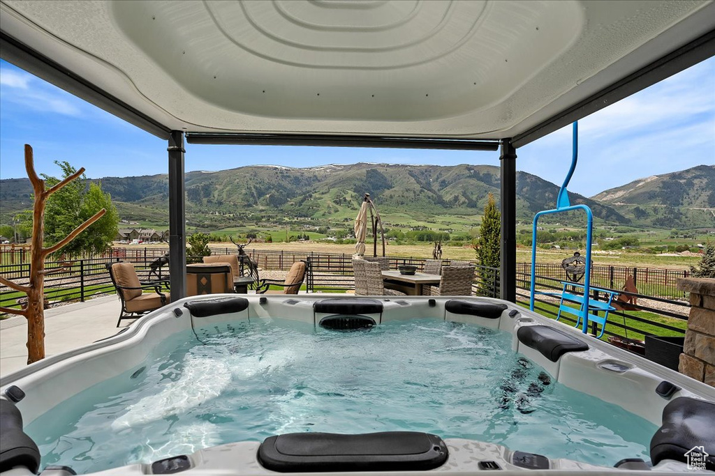 View of swimming pool with a hot tub, a mountain view, fence, and a view of countryside