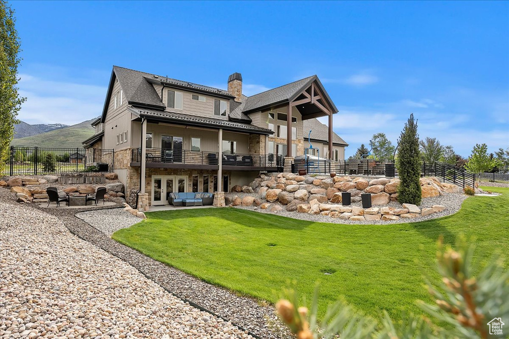 Rear view of property featuring stone siding, french doors, a chimney, a mountain view, and a patio