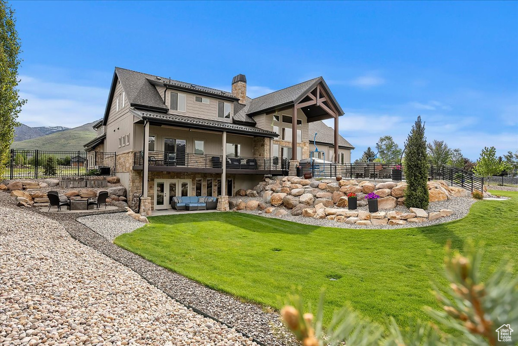 Rear view of house with stone siding, french doors, a chimney, an outdoor hangout area, and a mountain view