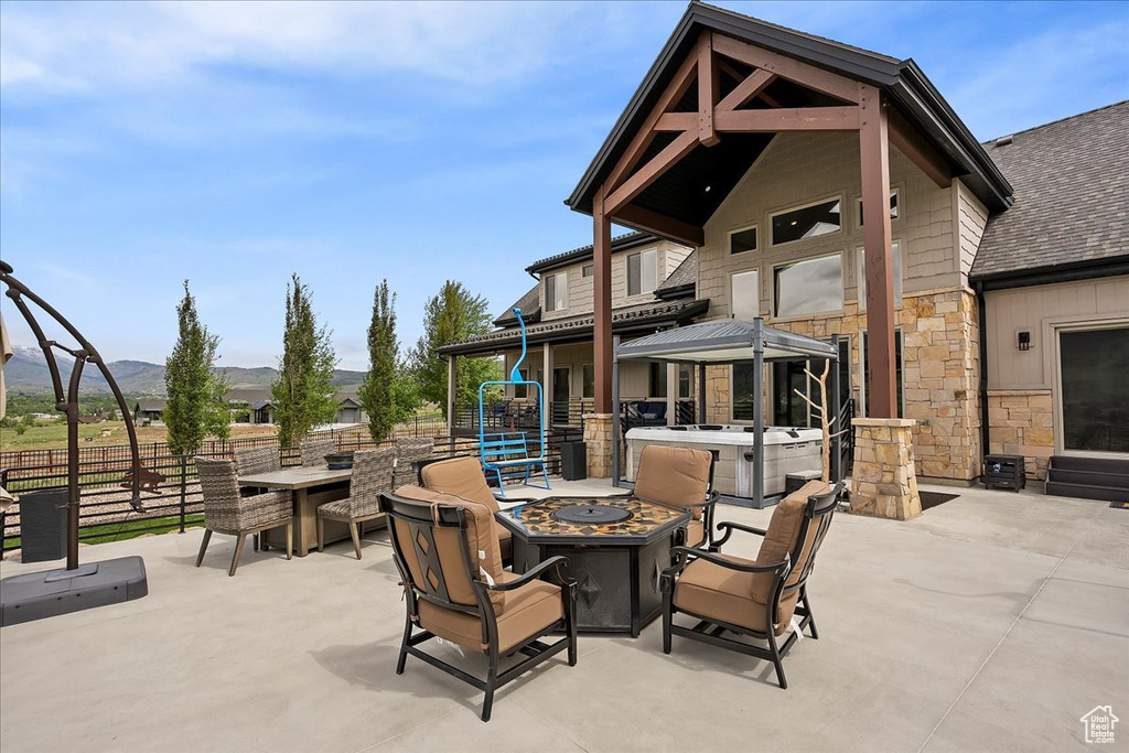 View of patio / terrace featuring an outdoor fire pit, a hot tub, fence, a mountain view, and a gazebo