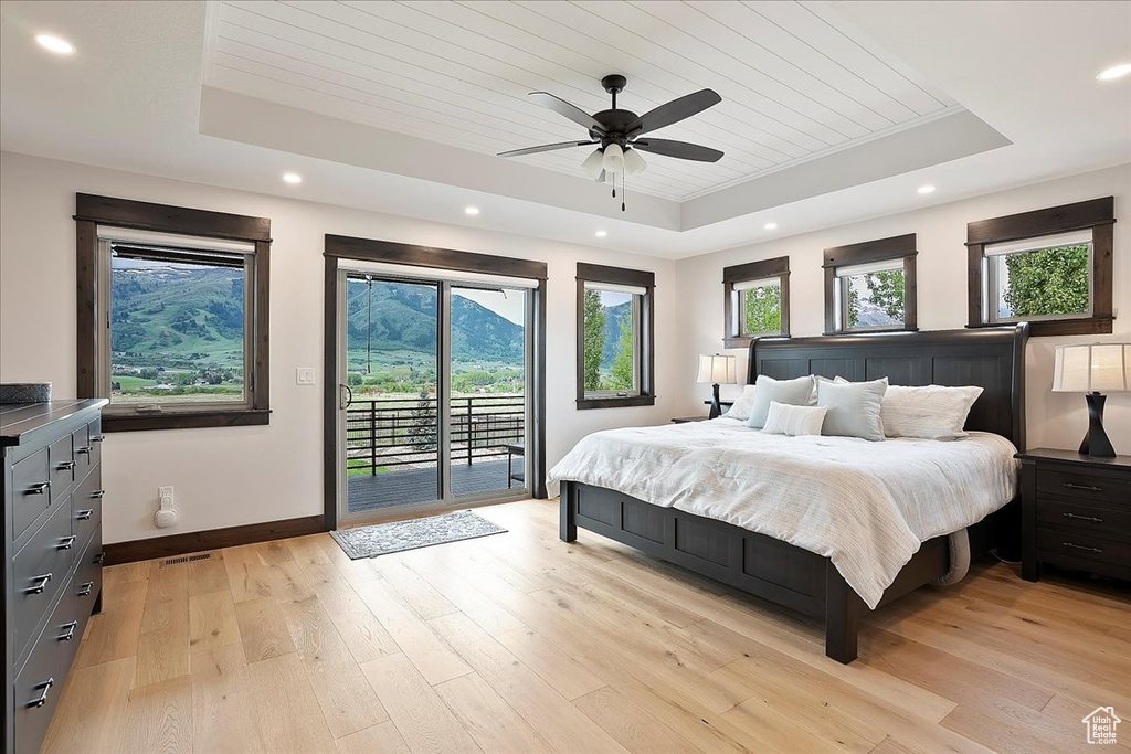 Bedroom featuring a tray ceiling, wooden ceiling, access to outside, light wood-type flooring, and baseboards