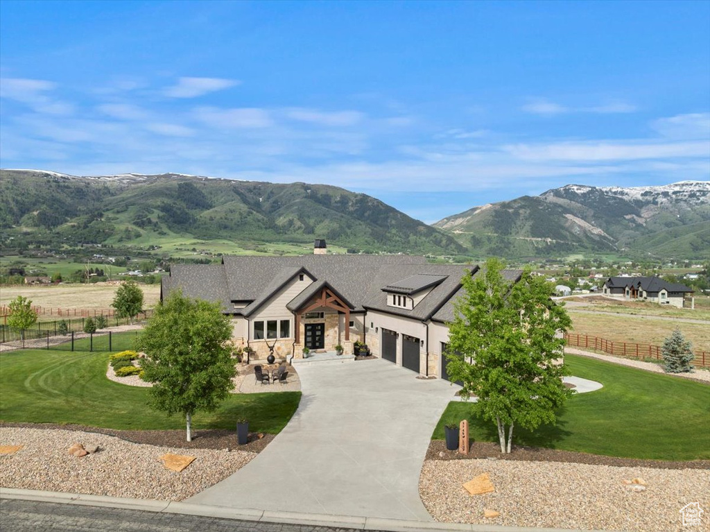 View of front of home featuring concrete driveway, a mountain view, an attached garage, stone siding, and a shingled roof