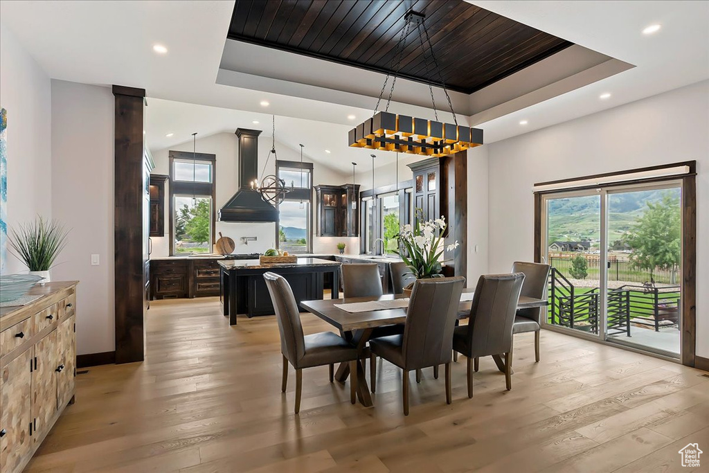 Dining room with a raised ceiling, recessed lighting, plenty of natural light, and light wood-type flooring
