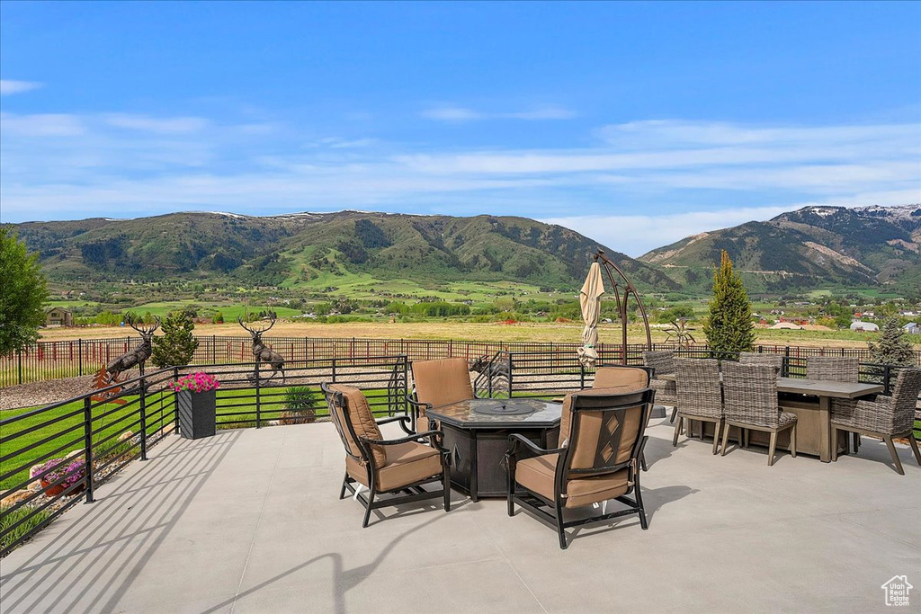View of patio featuring a fire pit, a mountain view, and fence