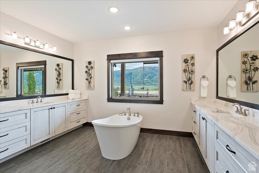 Full bath featuring baseboards, two vanities, a freestanding bath, and recessed lighting