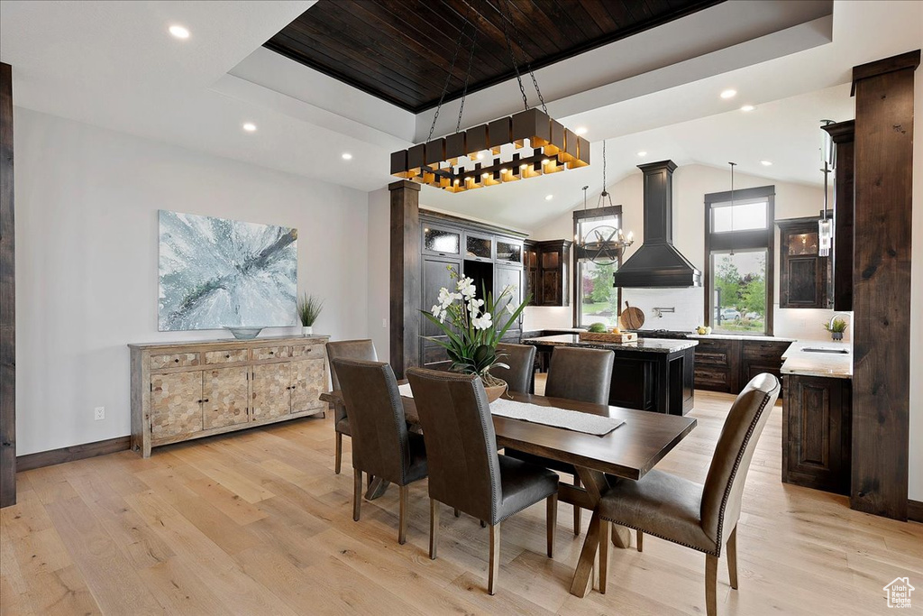 Dining area featuring light wood finished floors, a raised ceiling, recessed lighting, vaulted ceiling, and baseboards